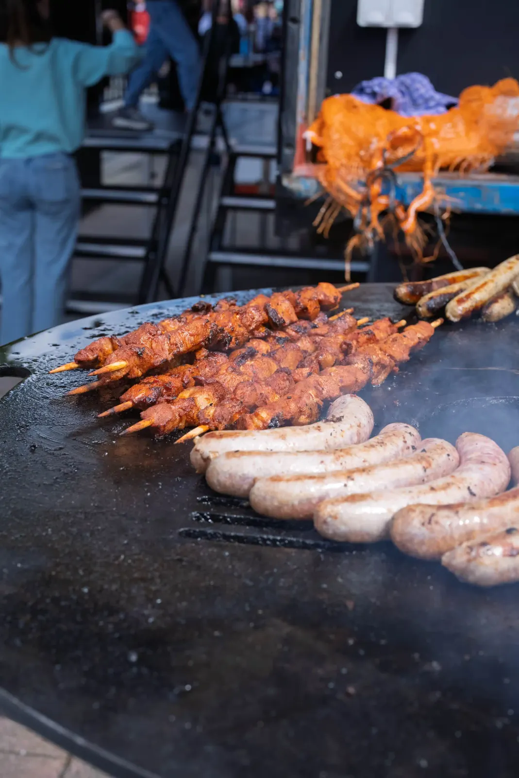 Spieße und Bratwürste auf der großen Feuerplatte