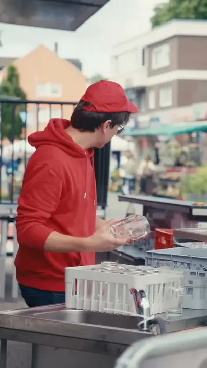 Servicekraft beim Spülen der Gläser am Fahrzeug