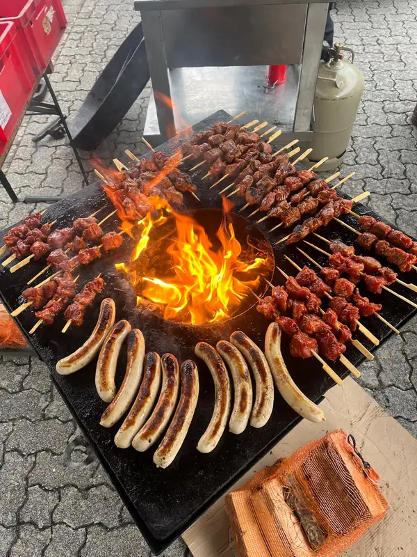 Spieße und Bratwürste rund um das offene Feuer