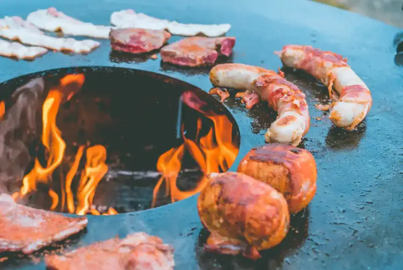 Bacon und Würstchen auf der Feuerplatte