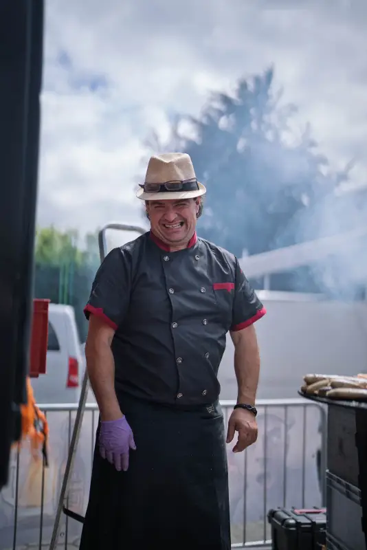 Grillmeister mit Strohhut an der Grillstation